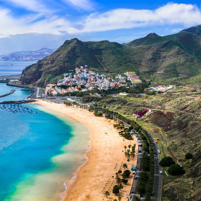 An aerial view of Lanzarote and a beach with mountains in the background.