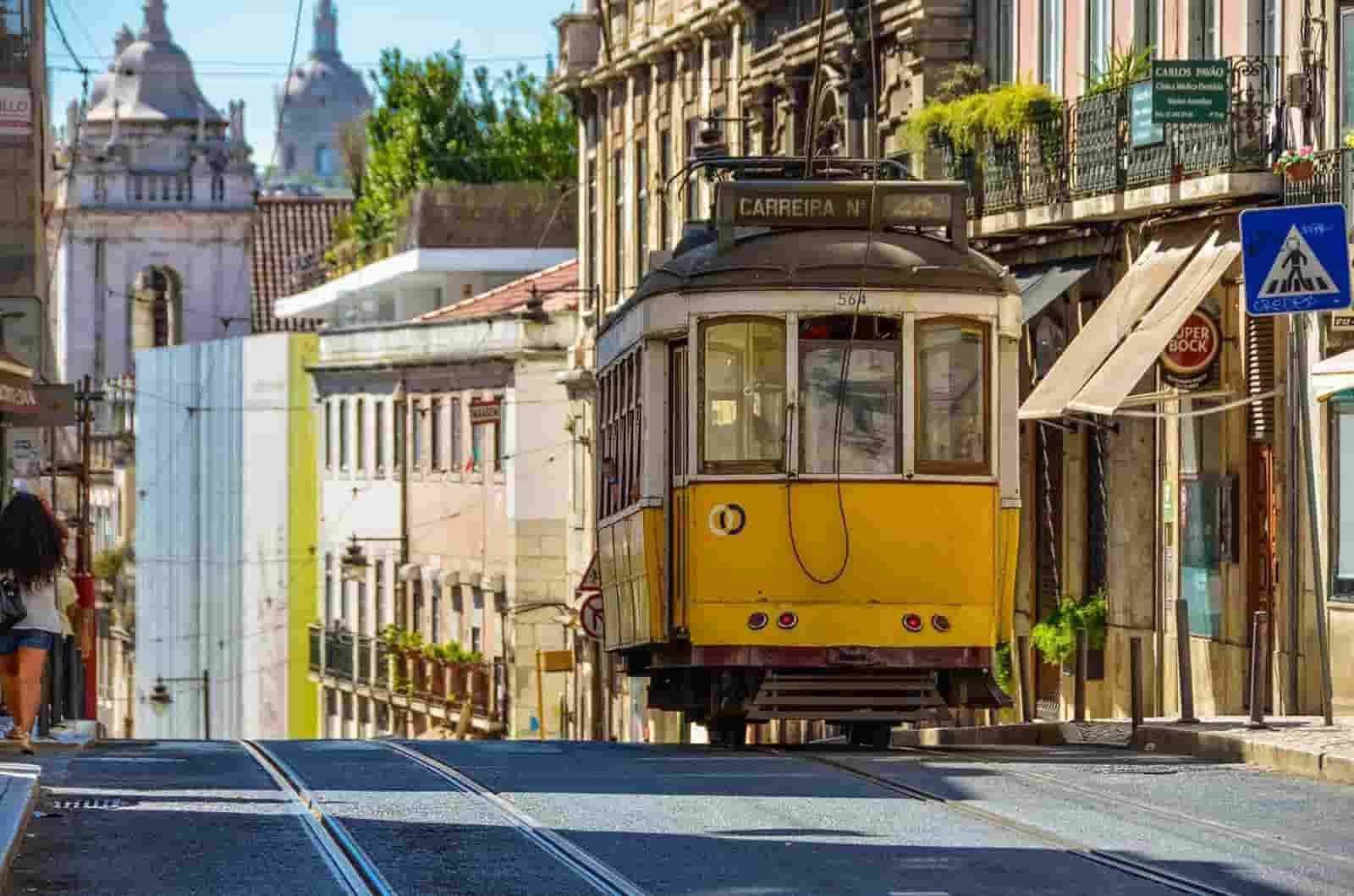 A yellow Lisbon trolley is driving down a city street.