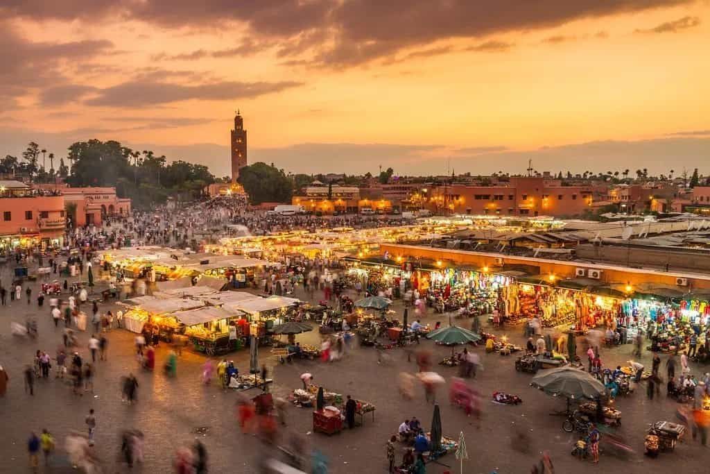 A large crowd of people are gathered in a square in Marrakesh.