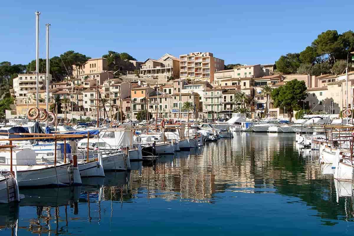 Boats are docked in a harbor with Soller in the background