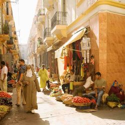 A woman is standing in a narrow street in Tangiers between two blue buildings.