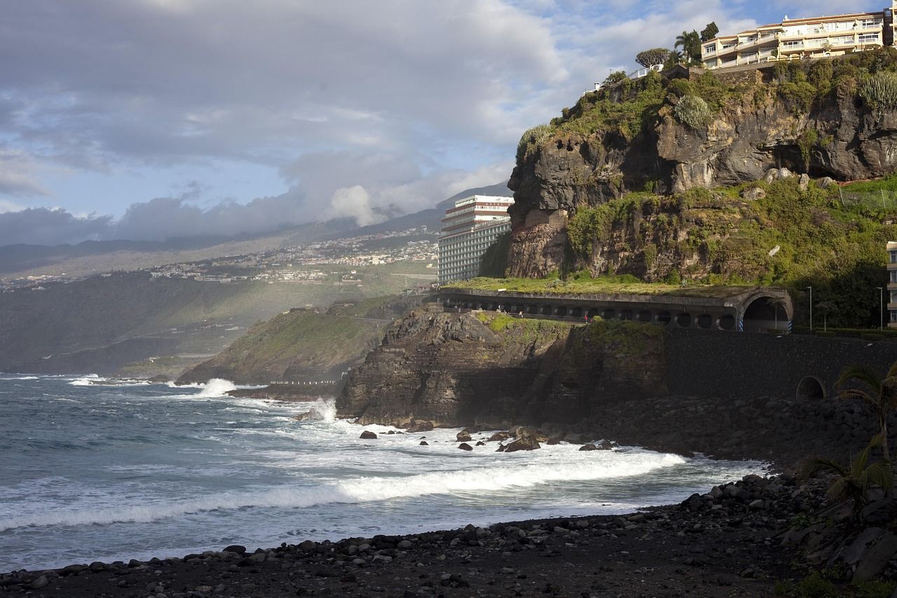 A cliff overlooking a body of water with a building in the background
