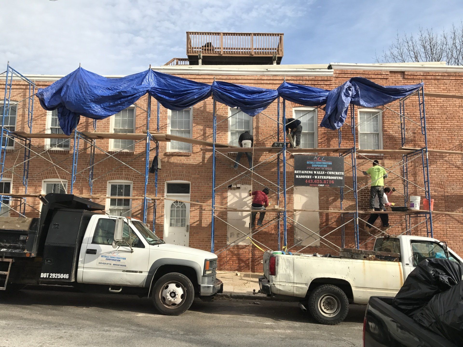 A crew providing exterior wall repair services on brick.