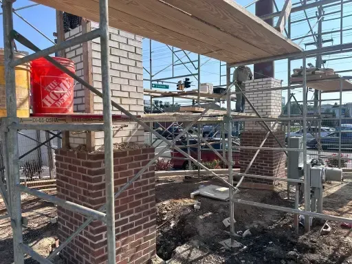 Chimney masonry repair project with scaffolding and workers.