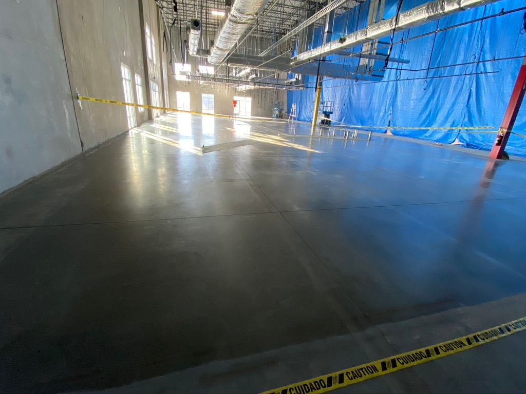 A large empty room with a blue curtain and a ladder.