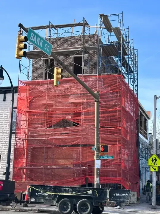 Commercial masonry work using scaffolding and safety netting.