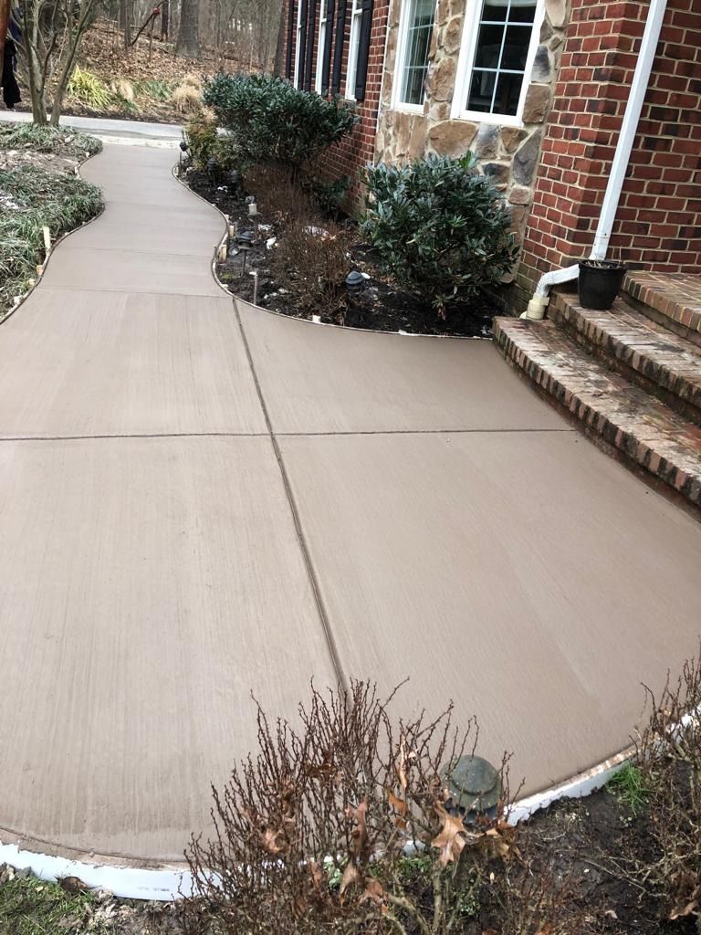A concrete walkway leading to a brick house.
