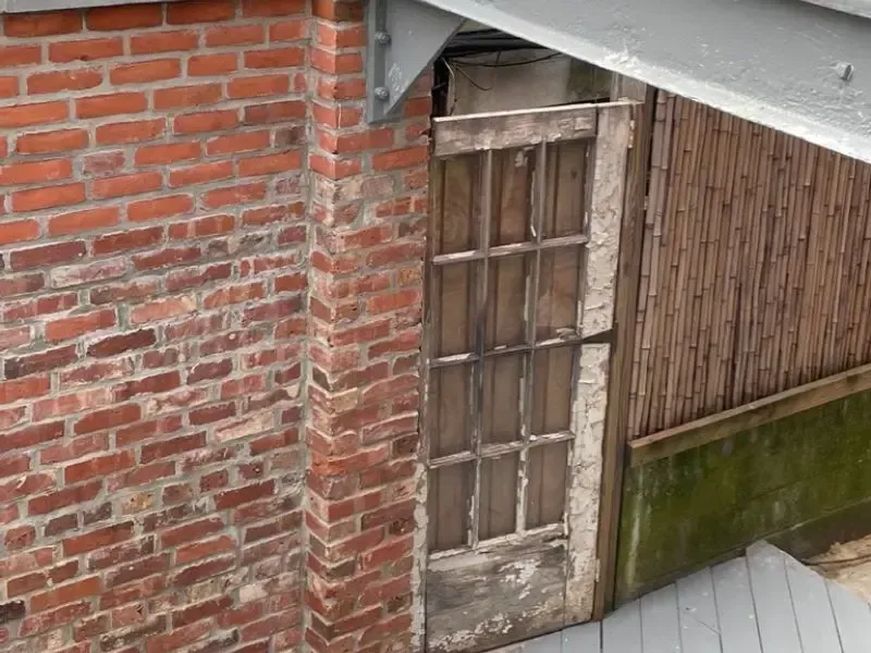 a brick wall with a wooden door and a bamboo fence