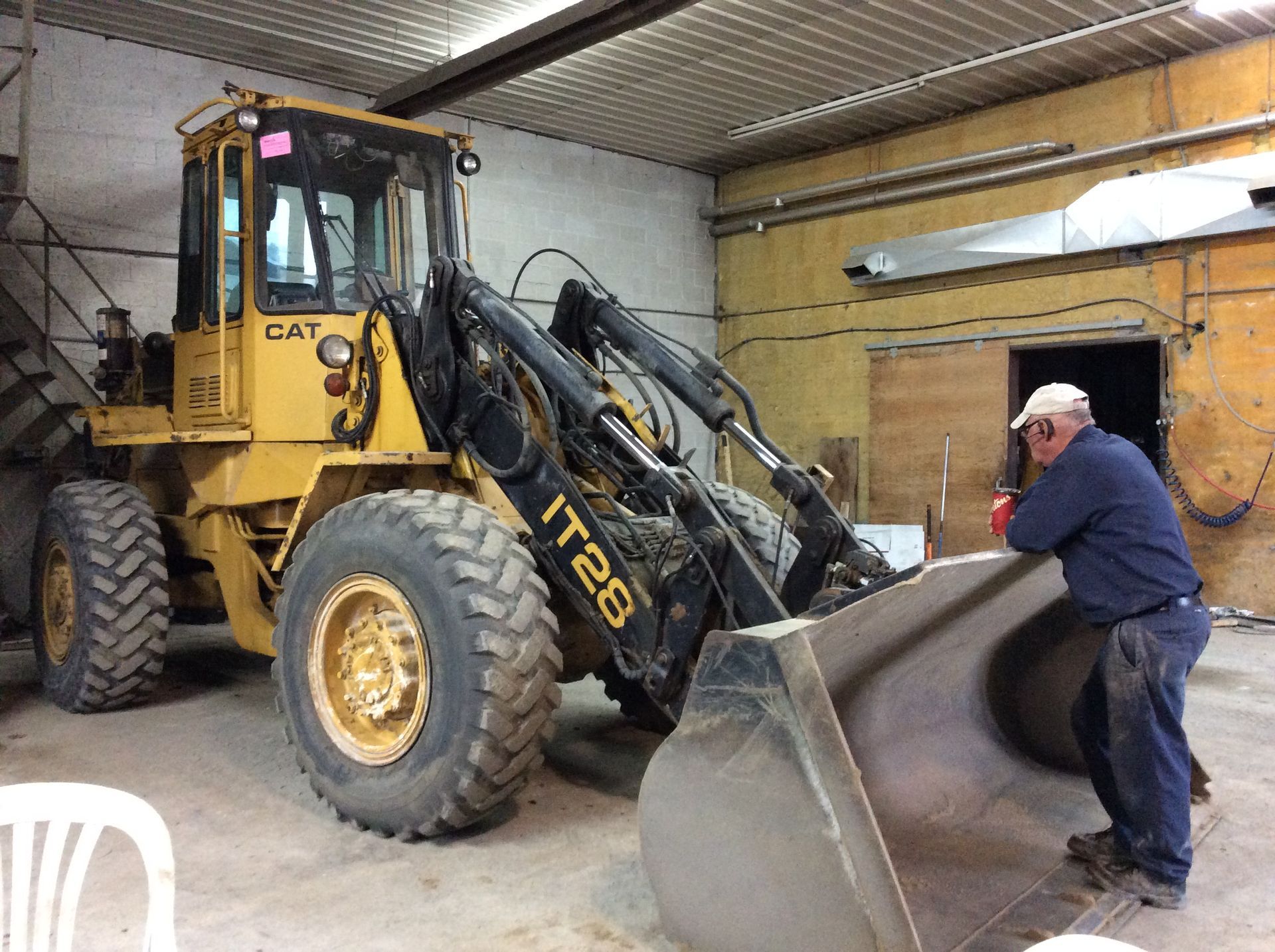 Un homme se tient à côté d'un bulldozer dans un garage.