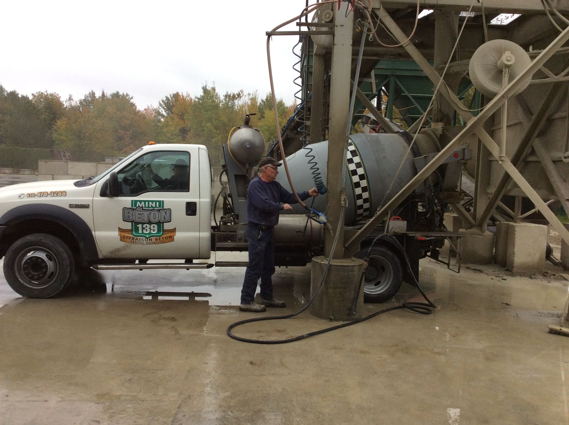 Un homme se tient à côté d'un camion malaxeur à béton.