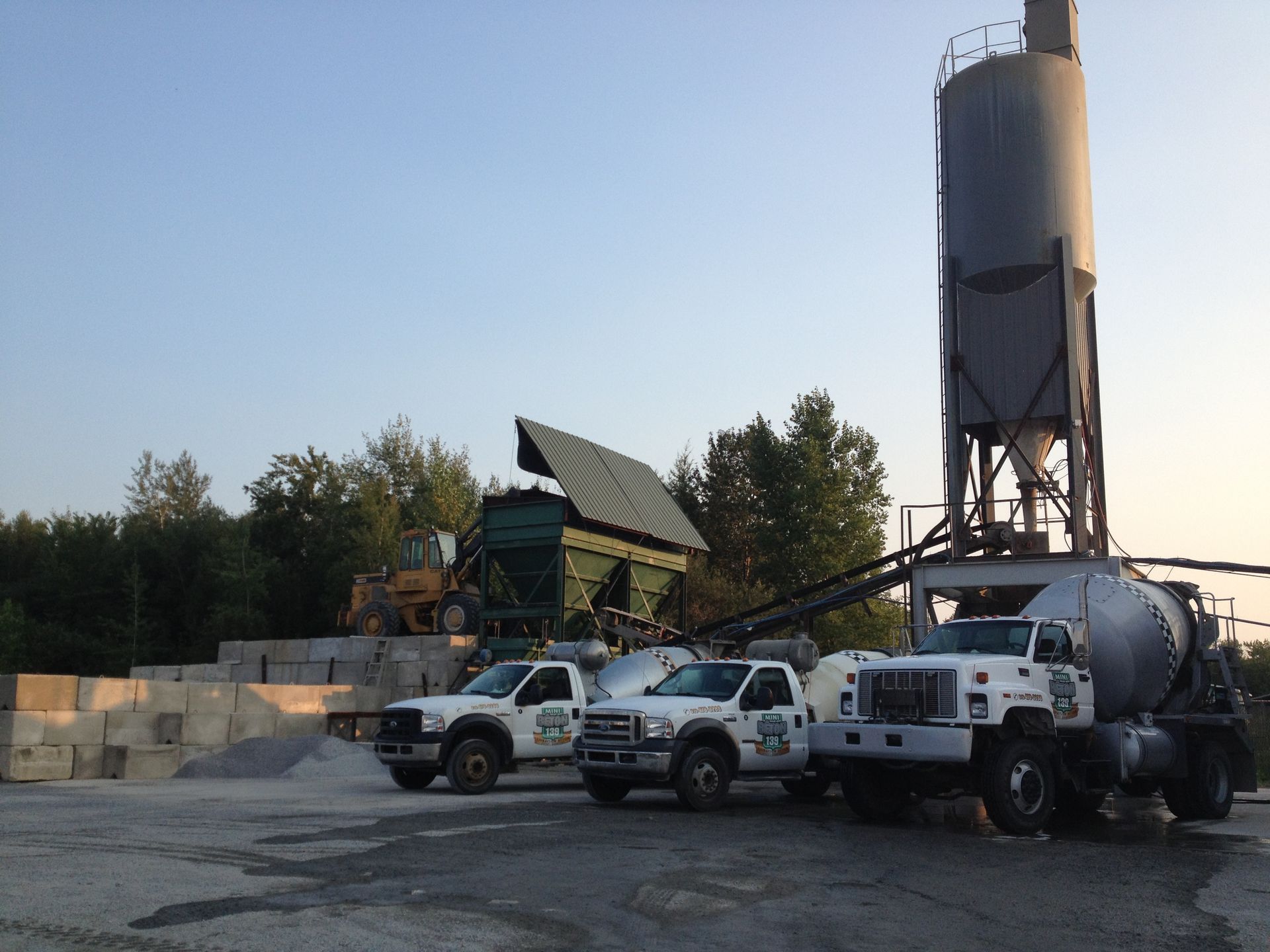 Plusieurs camions sont stationnés devant un silo à ciment