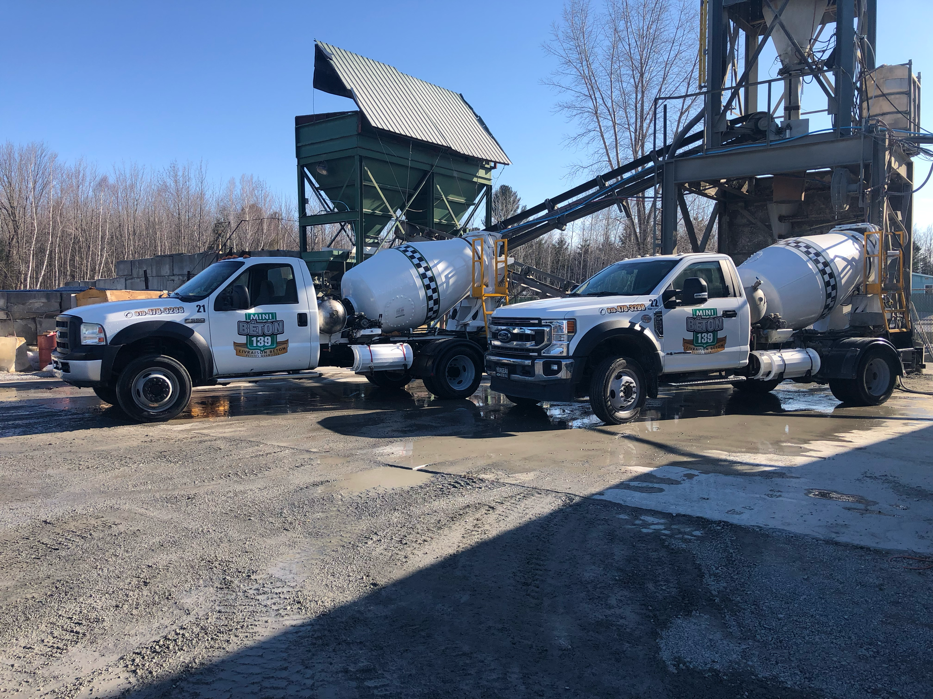 Deux camions sont garés l'un à côté de l'autre sur un terrain en gravier.