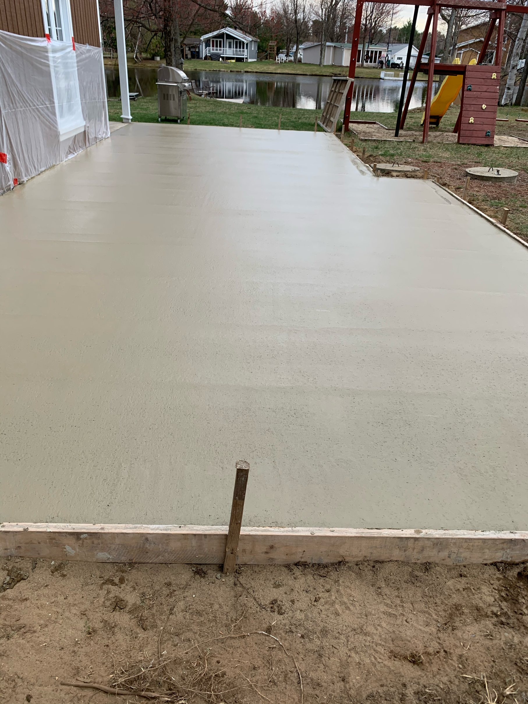 Une allée en béton est en cours de construction à côté d'une aire de jeux.