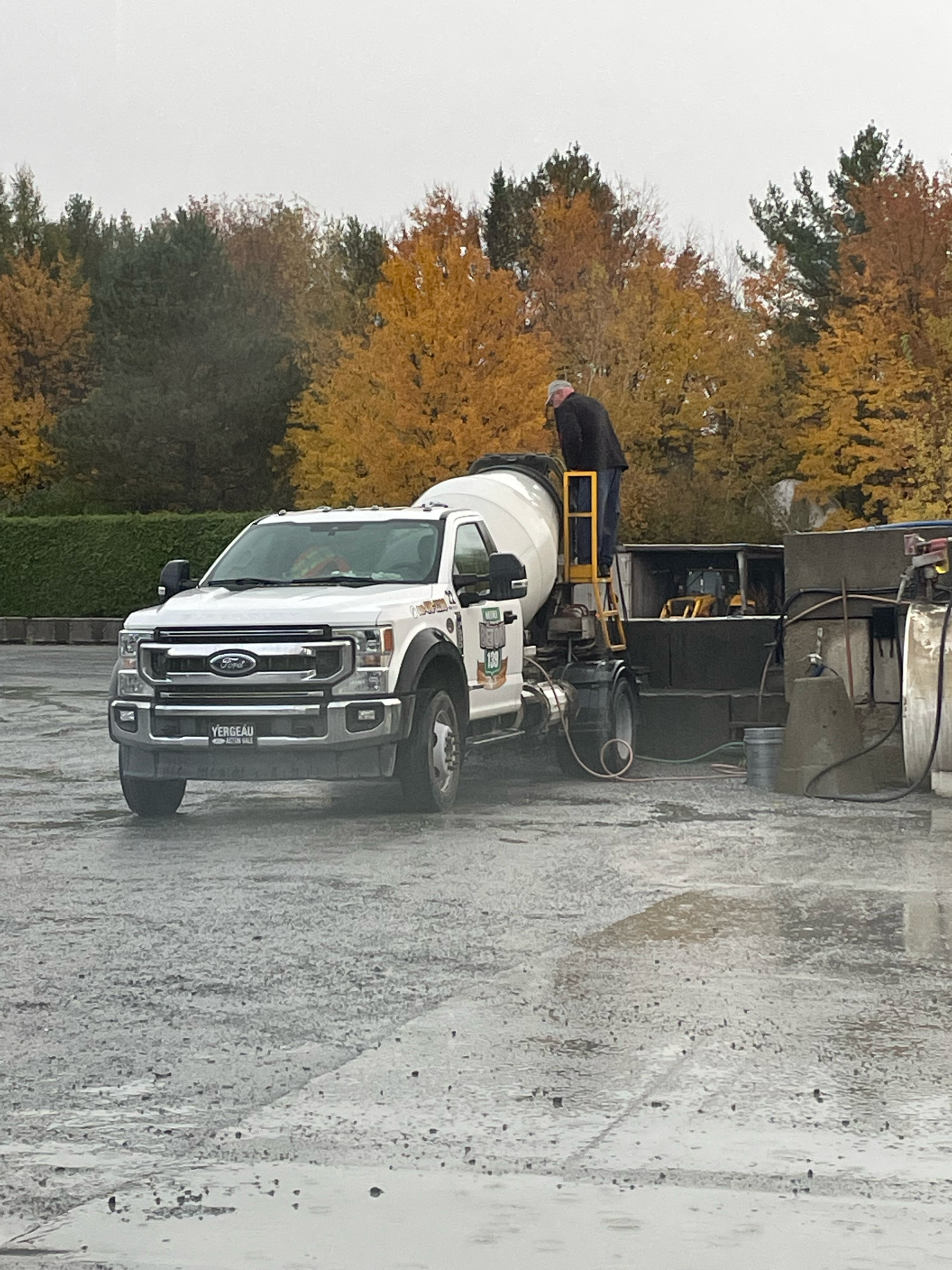 Un camion blanc roule à travers un champ boueux.