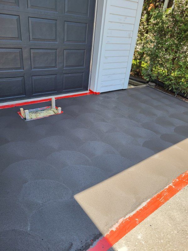 Une allée en béton est en train d'être peinte devant une porte de garage.