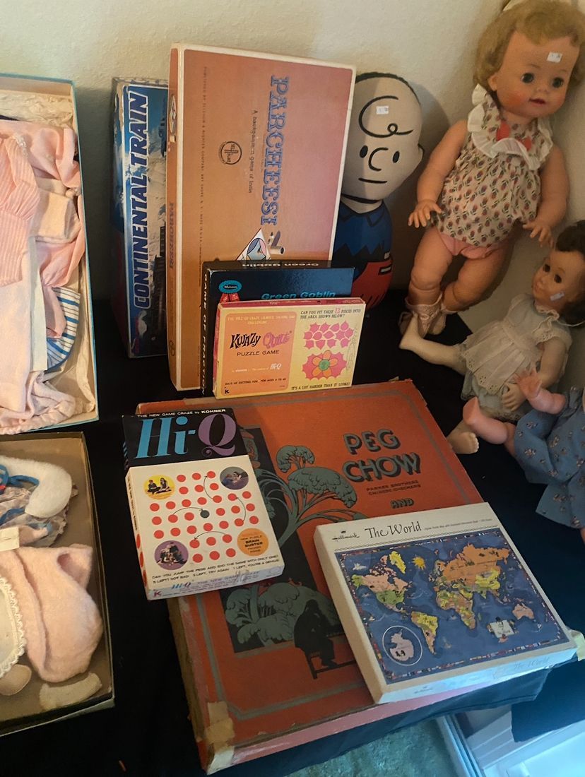 Collection of vintage children's items, including books, dolls, and a math game, on a table.
