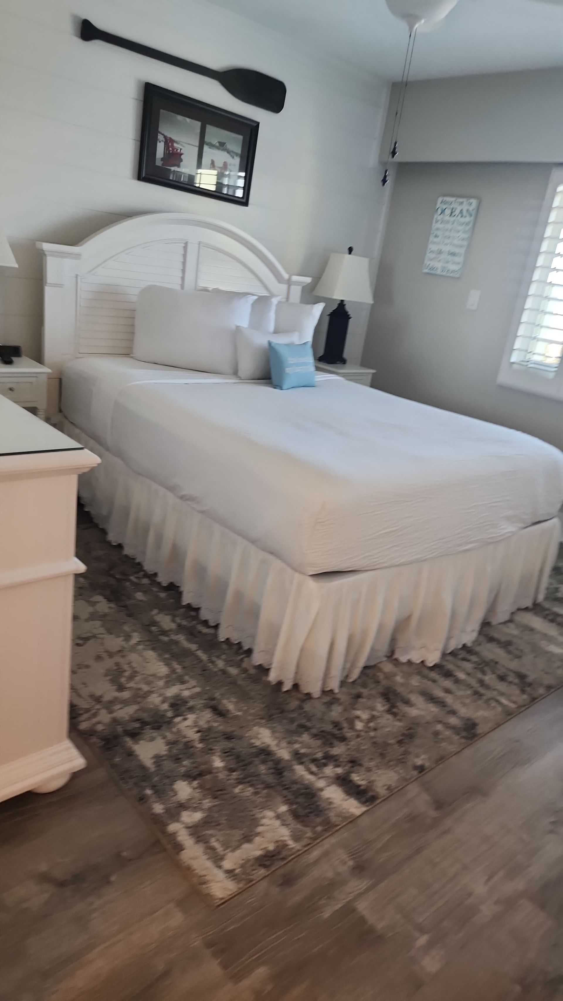 Bedroom with white furniture, gray rug, and decorative oar.