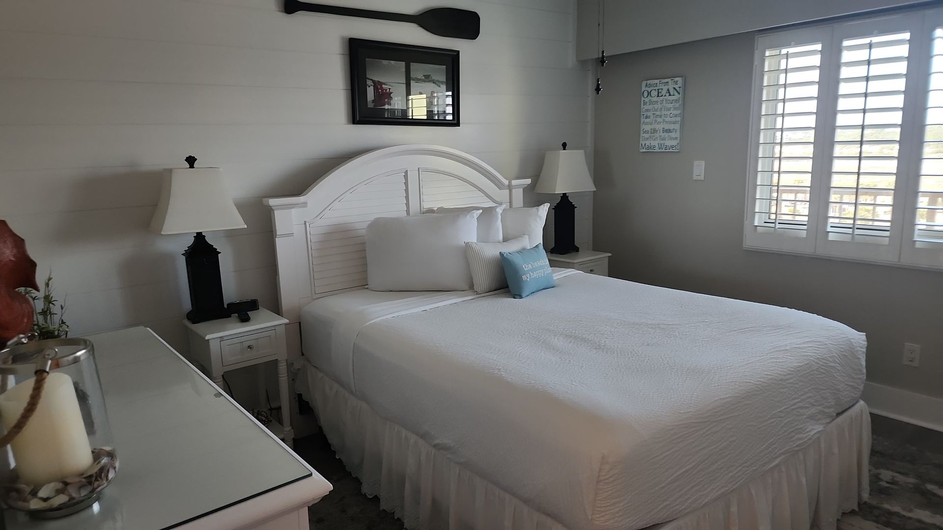 Bedroom with white bed, lamps, and coastal decor.