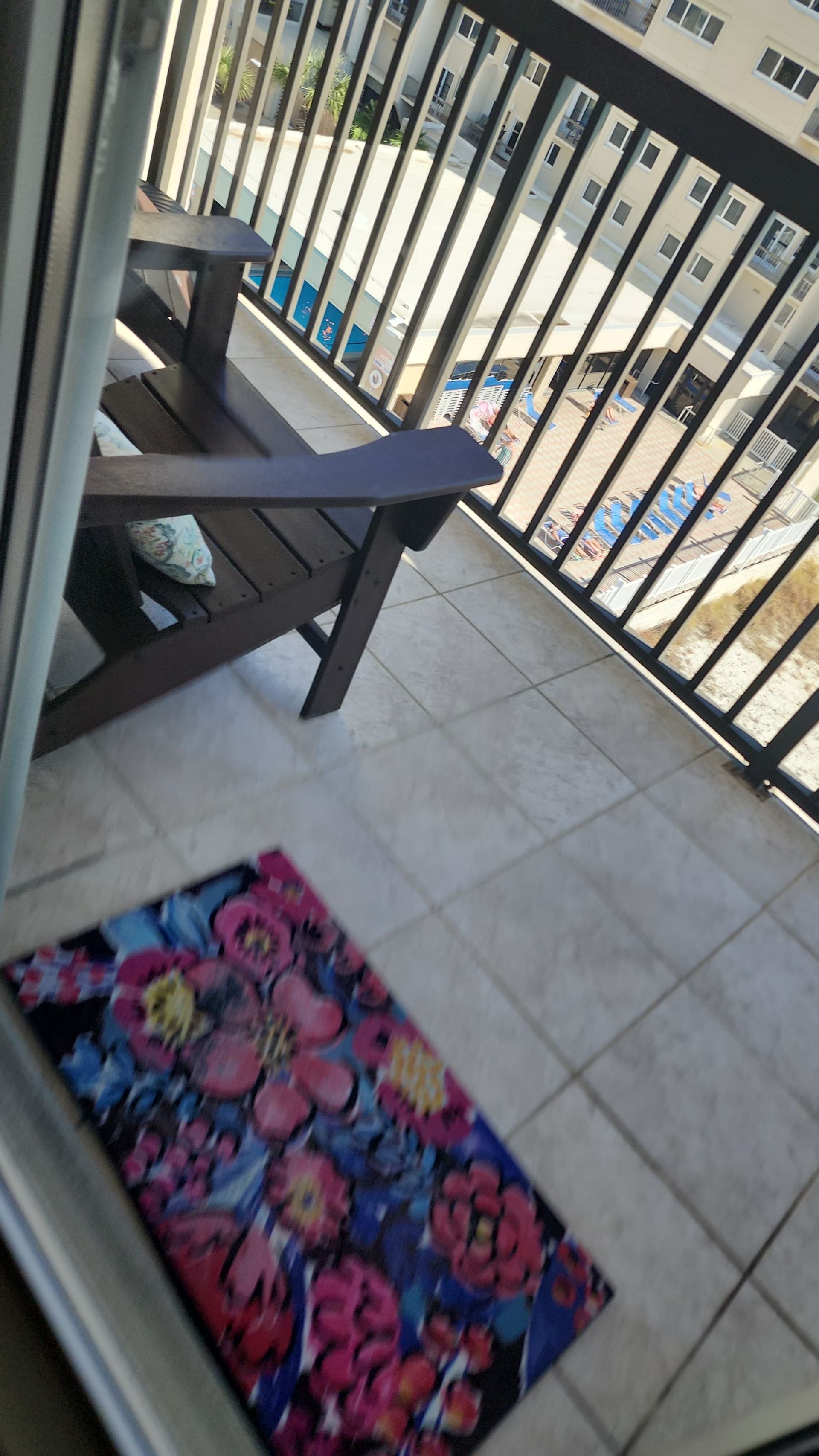 Balcony with dark wood chairs, floral rug, and city view.