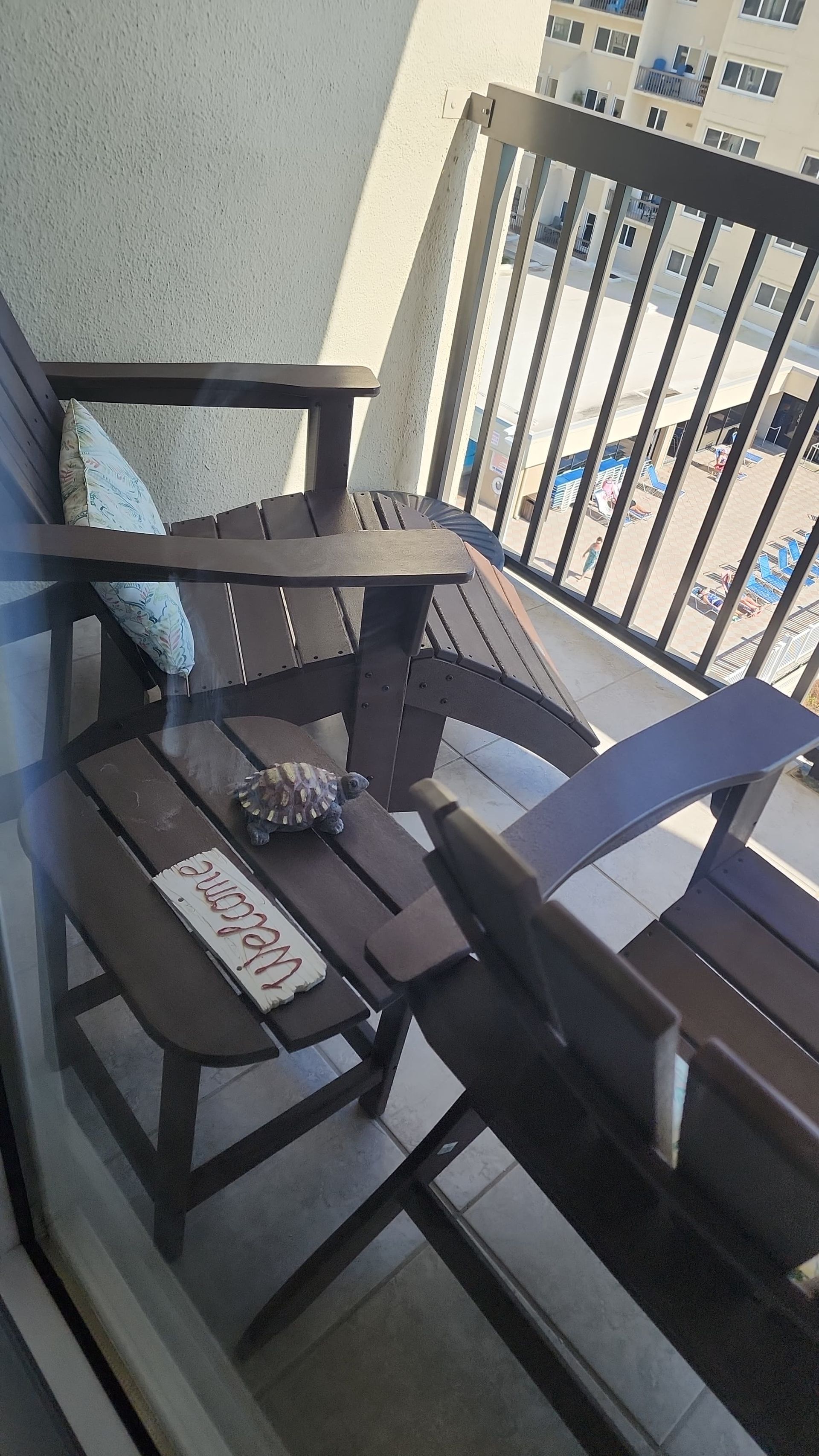 Two dark brown Adirondack chairs on a balcony, small tortoise on the center table.