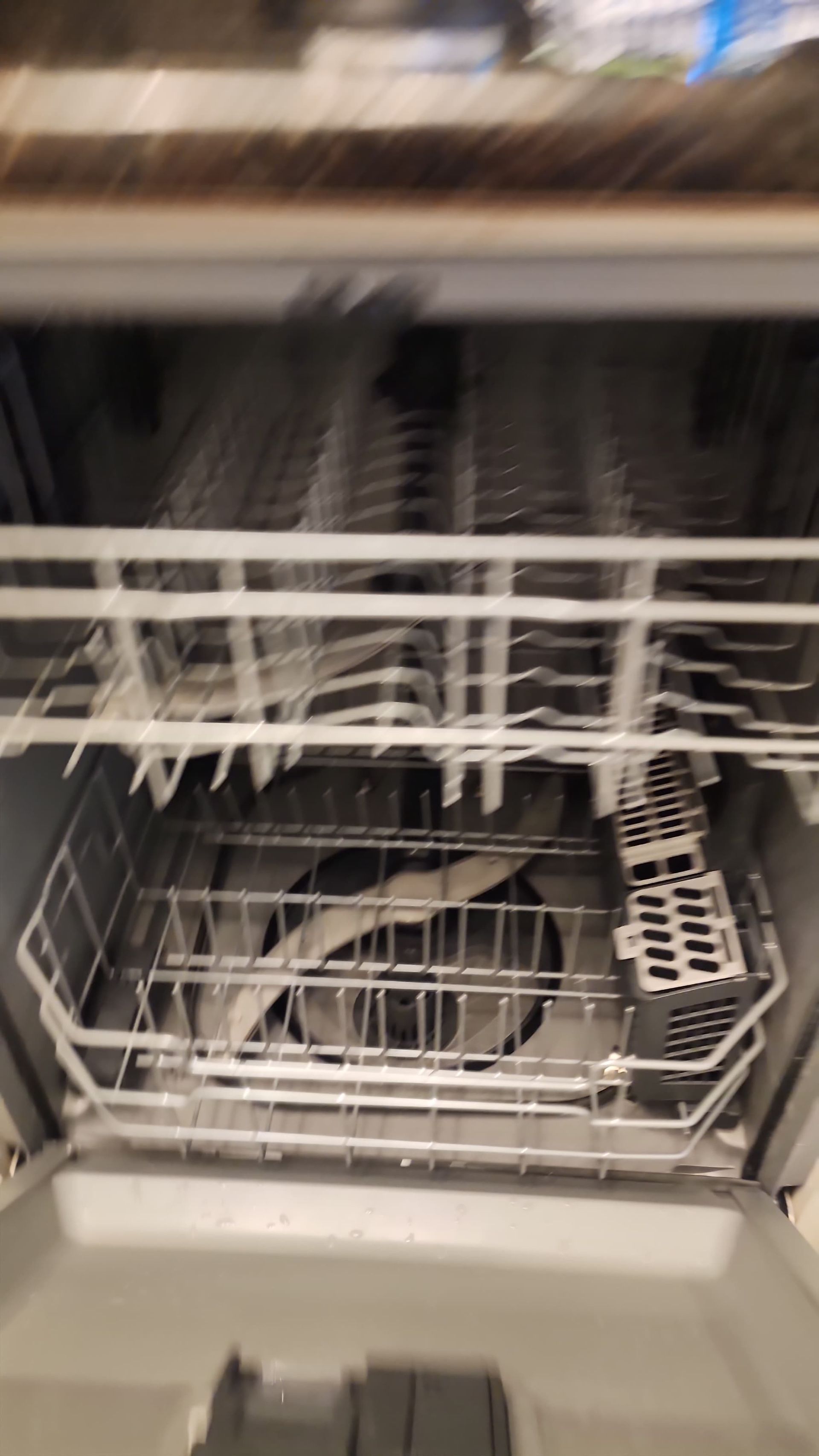Open dishwasher interior with racks and sprayer arm.