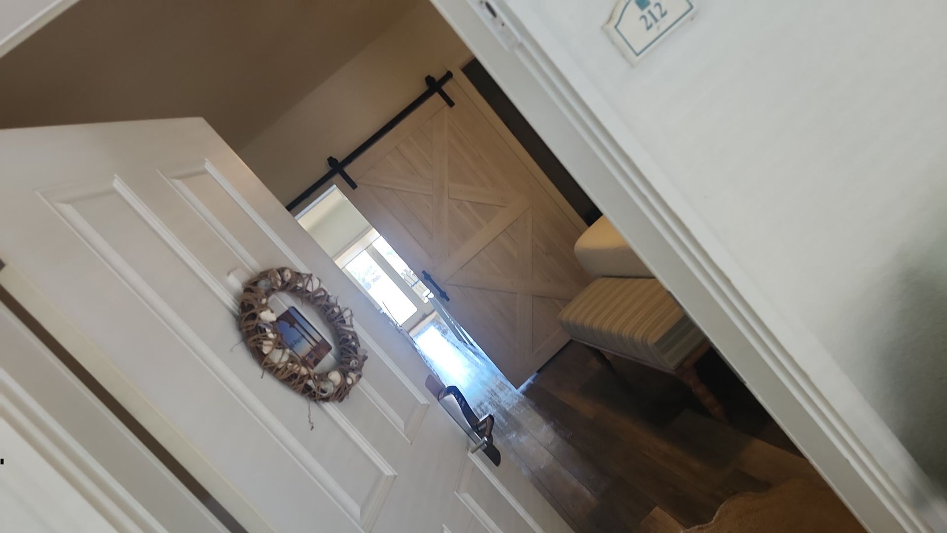 White door, barn door, hallway with wood floors and a wreath.