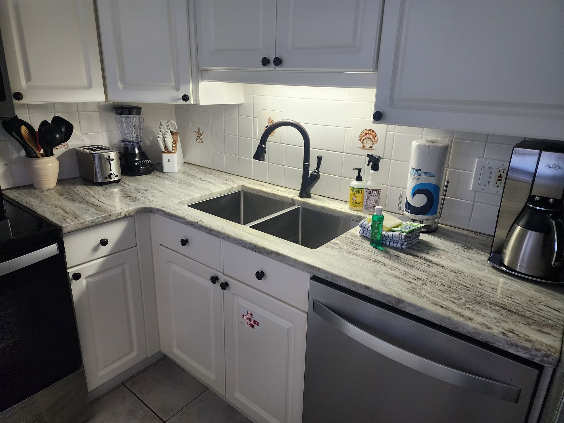 Kitchen with white cabinets, stainless steel sink, and appliances.