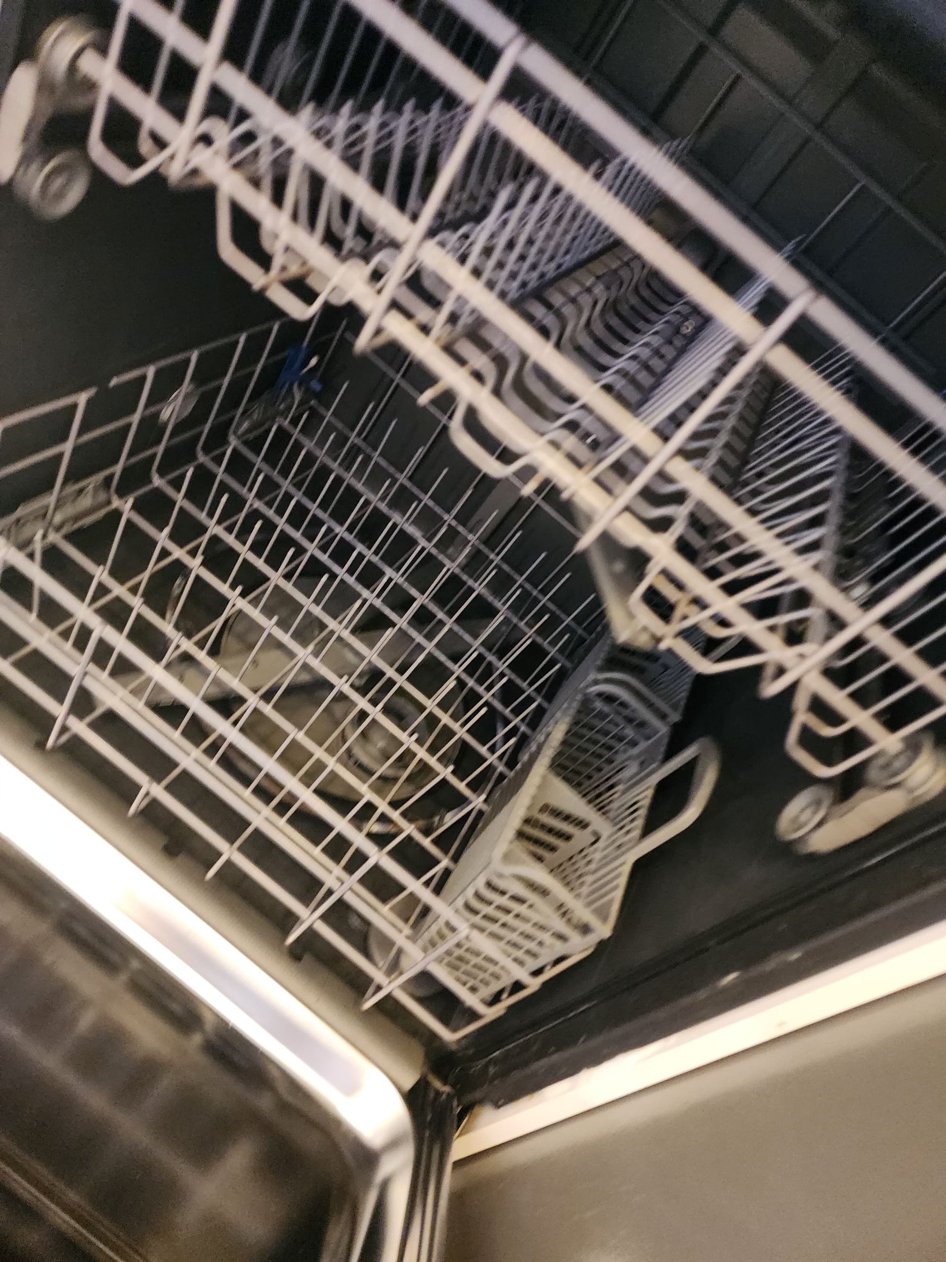Inside a dishwasher; racks with metal grids and a silverware basket.