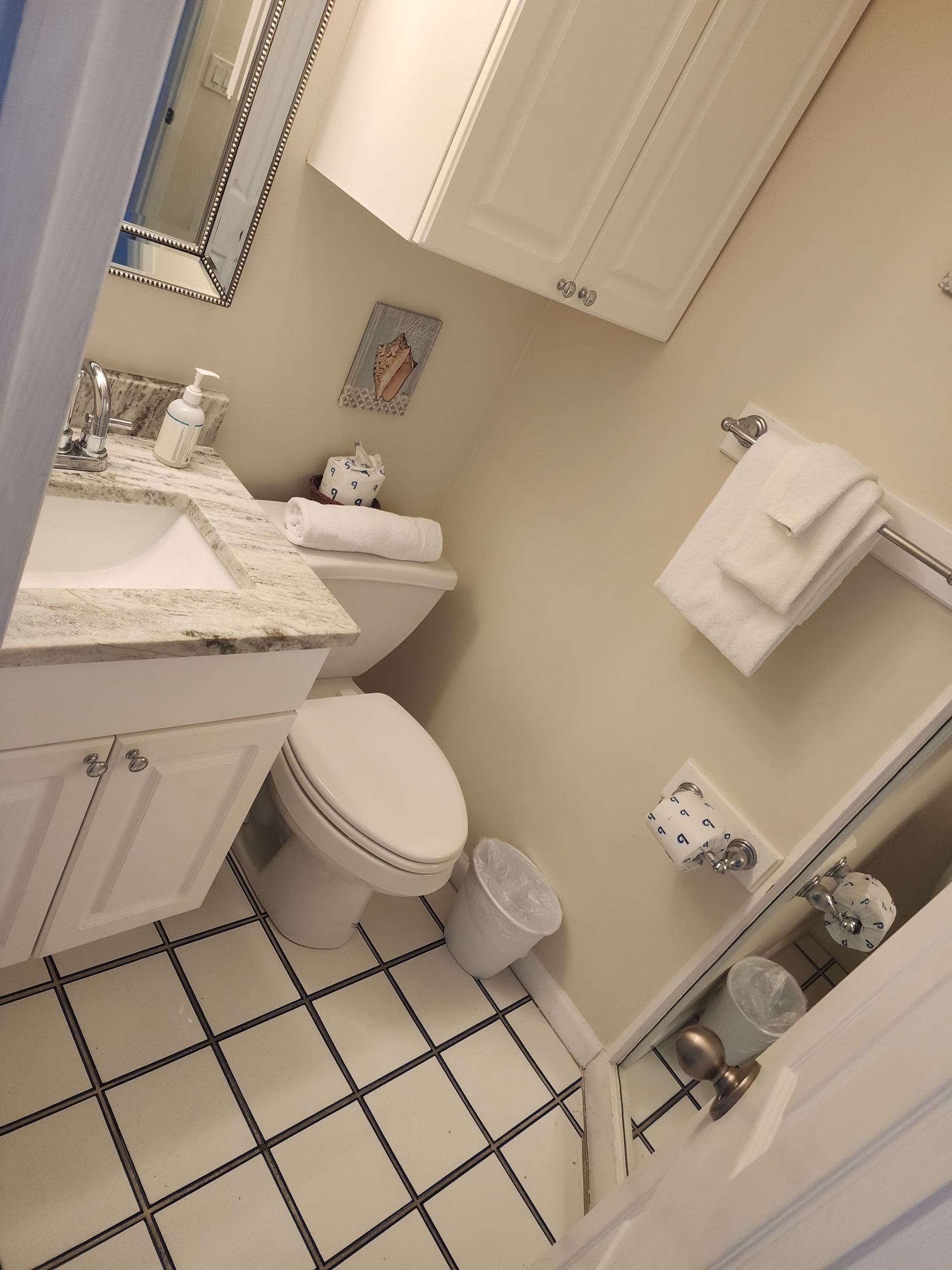 Small white bathroom with white tile floor, white cabinets, and white fixtures.