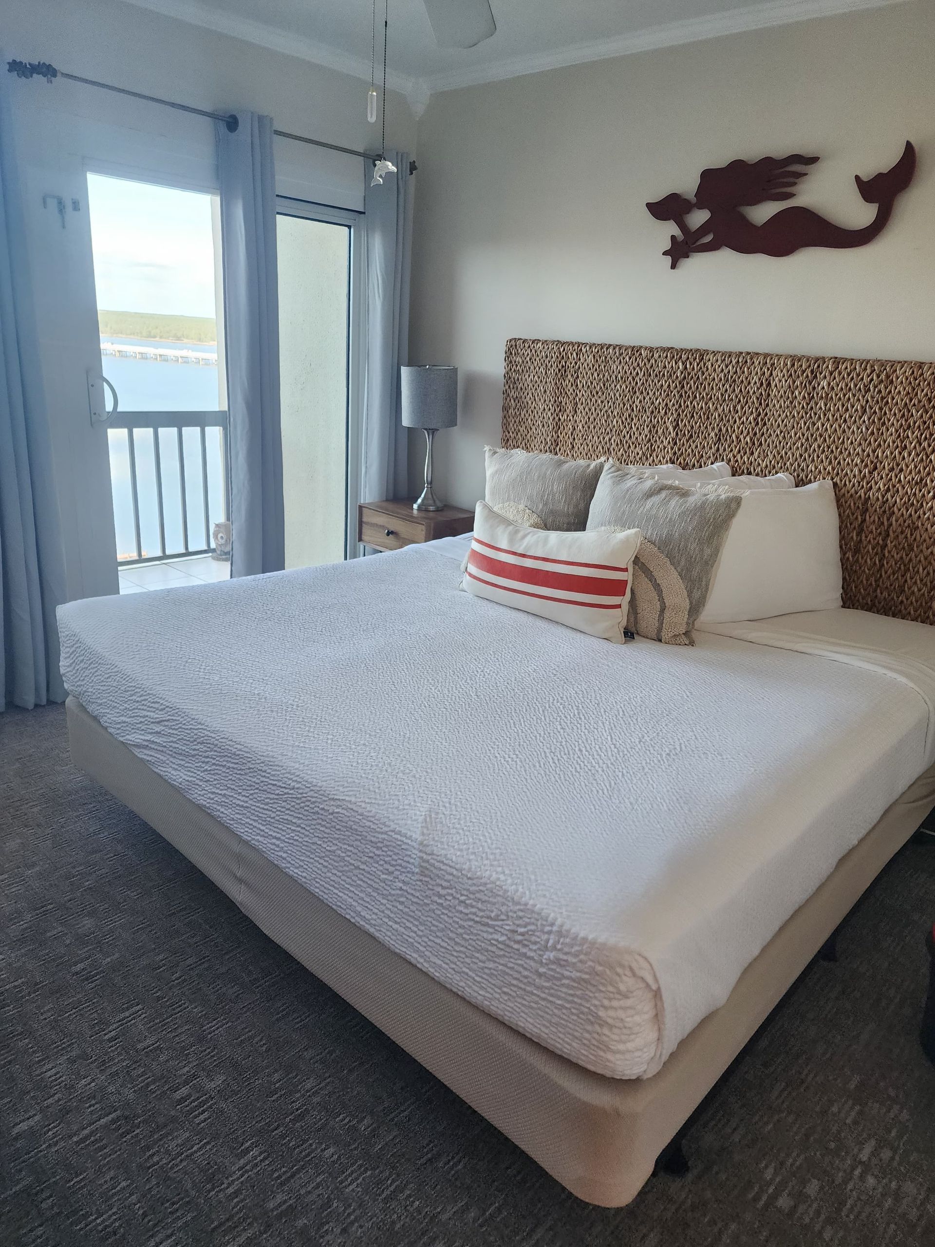 Bedroom with a bed, woven headboard, balcony access, and mermaid wall art.