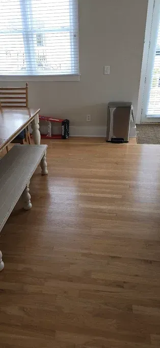 Wooden floor, table with bench, windows, and a heater.