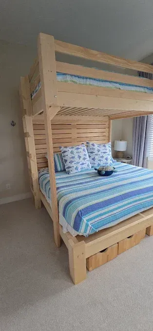 Light wood bunk bed with blue striped bedding, two pillows, and two pull-out drawers.