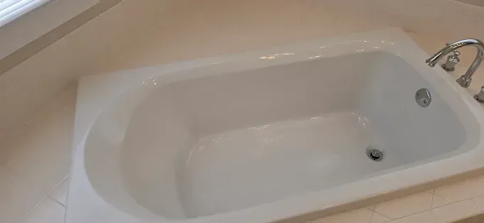 White bathtub with chrome faucet in a light-colored bathroom.