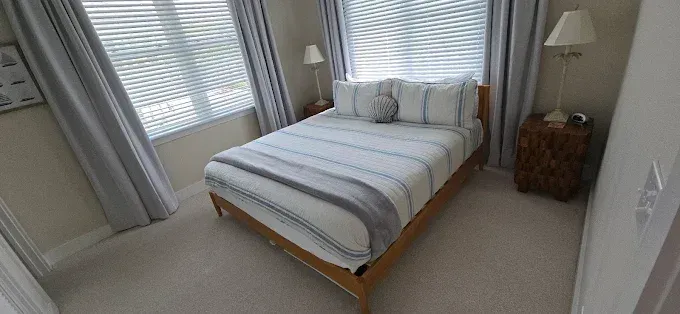 Bedroom with a bed, two bedside tables, and curtains. The bed is made with striped bedding.