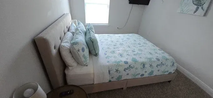 Bedroom with a bed, white walls, window, and decorative pillows.