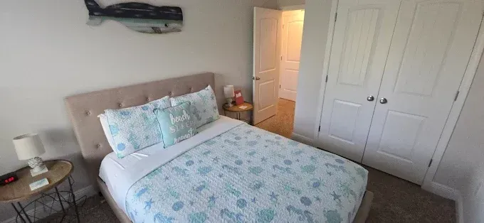 Bedroom with a bed, closet, and a whale decoration on the wall. Turquoise and beige colors dominate.