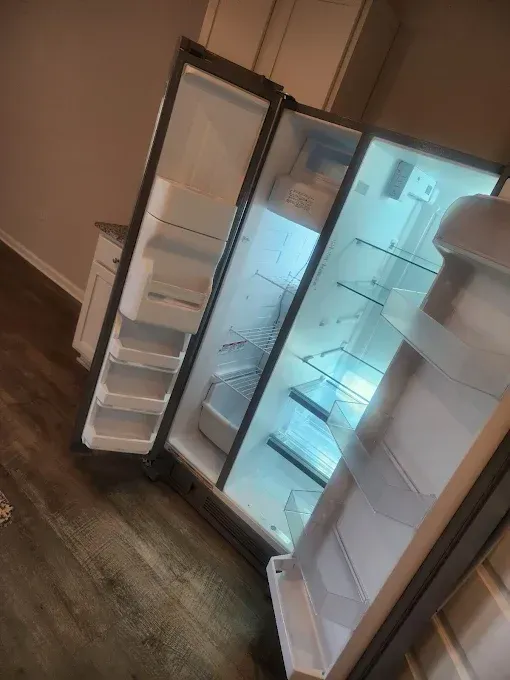 Open refrigerator with illuminated interior, revealing shelves and drawers.