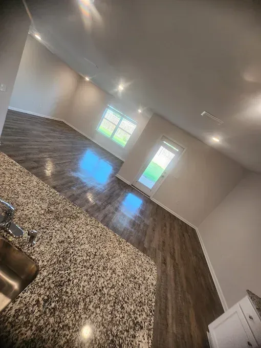 Kitchen with granite countertop, wood floor, windows, and door; natural light.