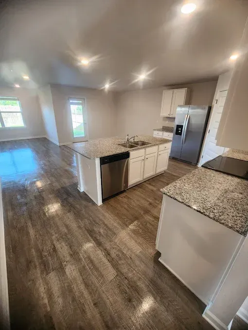 Kitchen with island, stainless steel appliances, hardwood floors, and white cabinets.