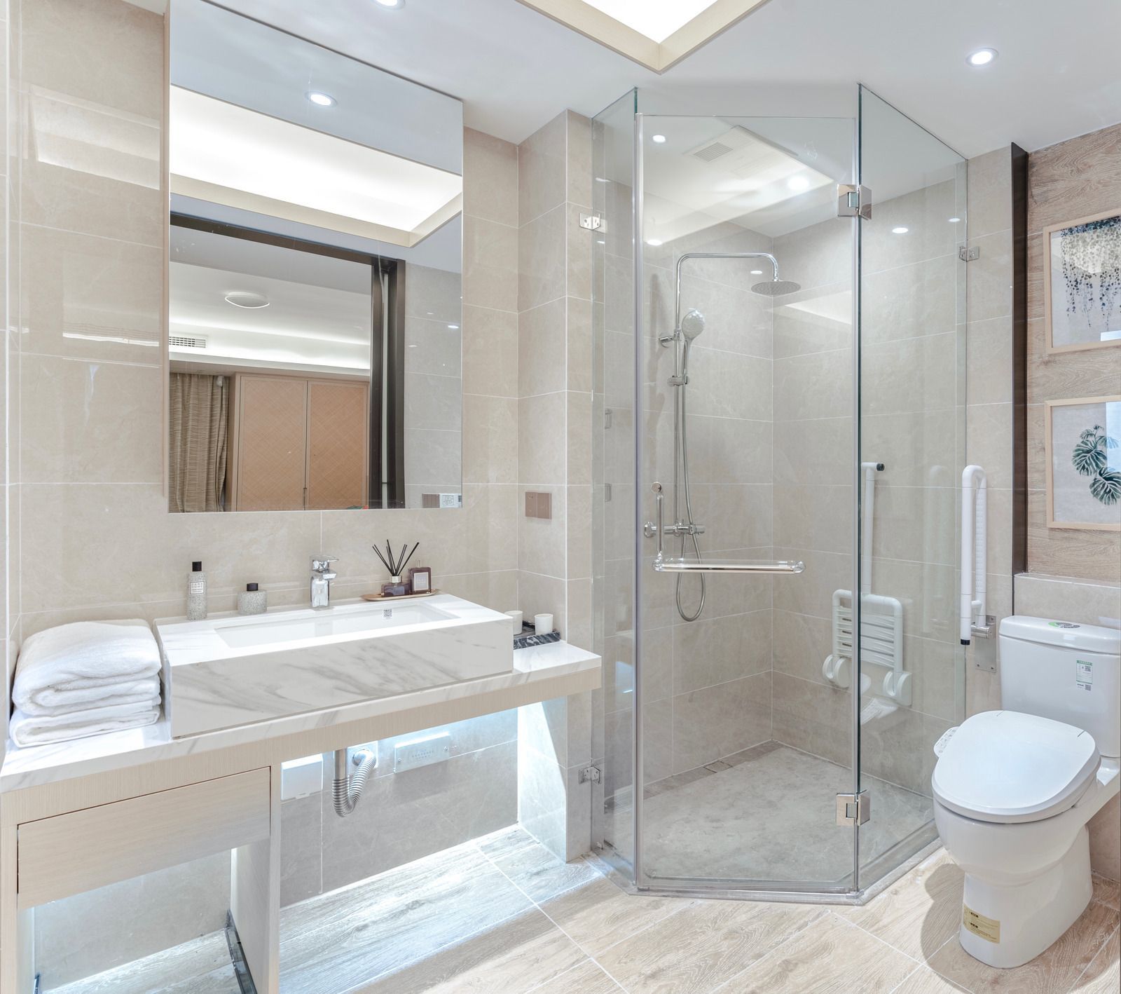 Beige bathroom with marble countertop, large mirror, glass shower, and toilet.