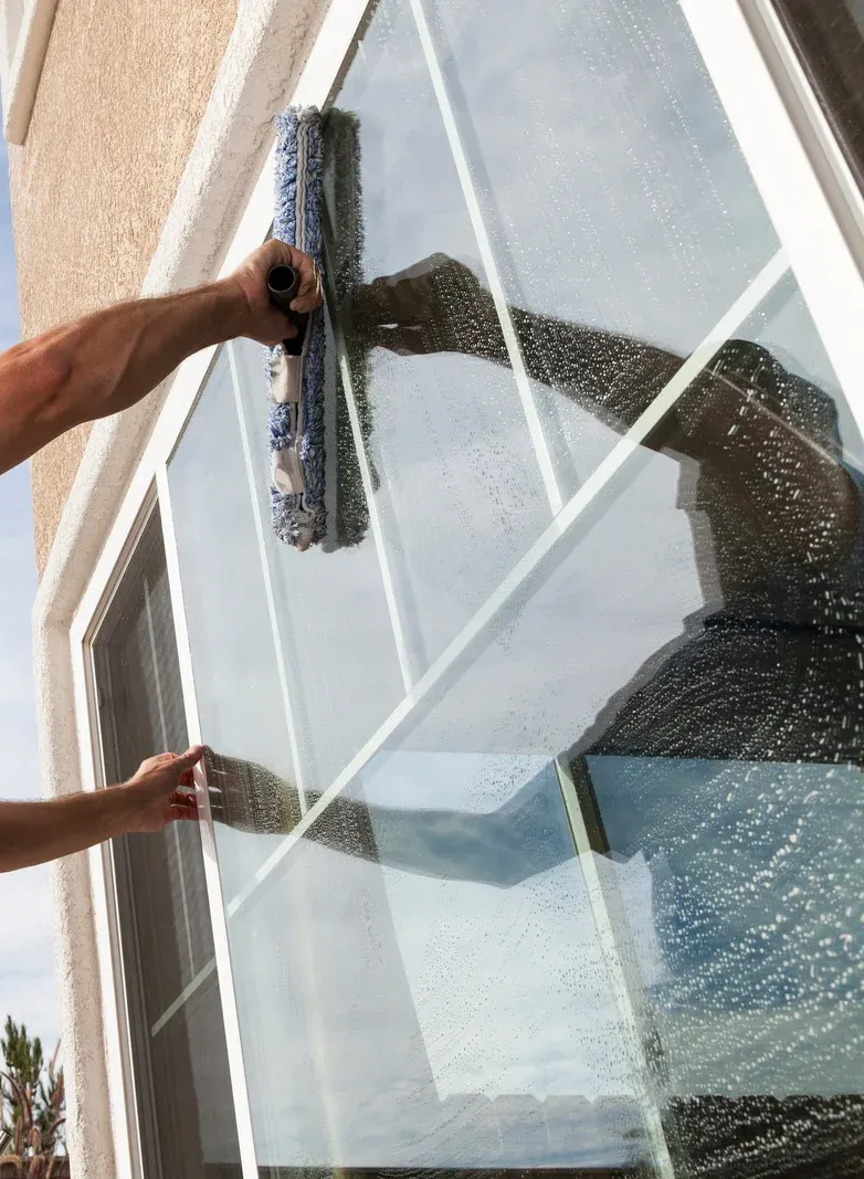 Person cleaning a multi-pane window with a squeegee.