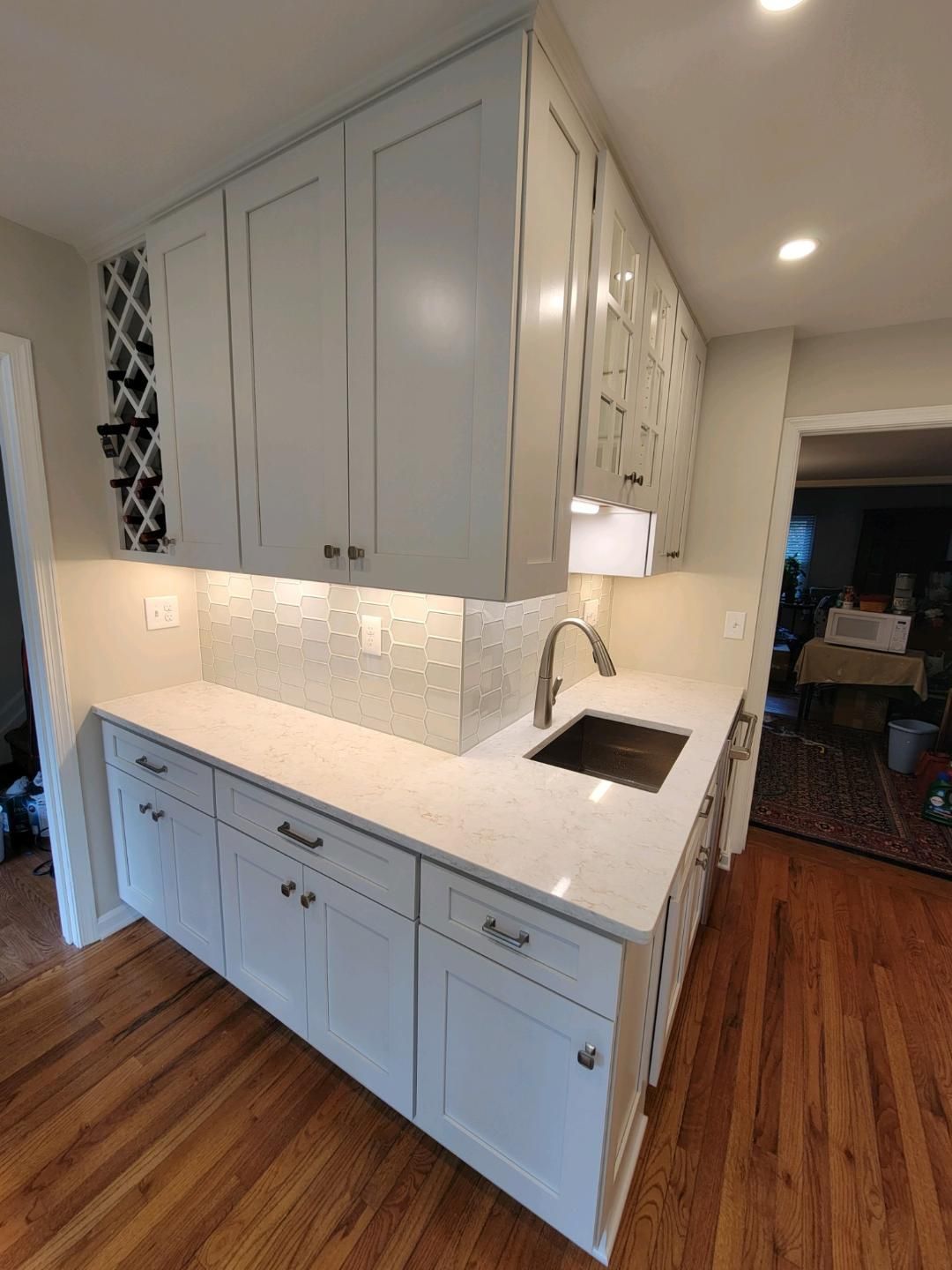 White kitchen cabinets with a marble backsplash and a dark sink.
