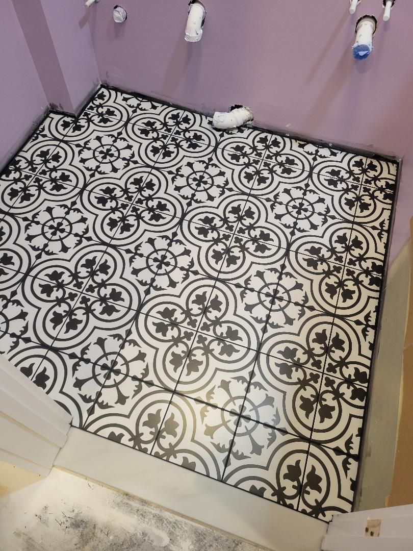 Bathroom floor tiled in black and white floral pattern; partially installed.