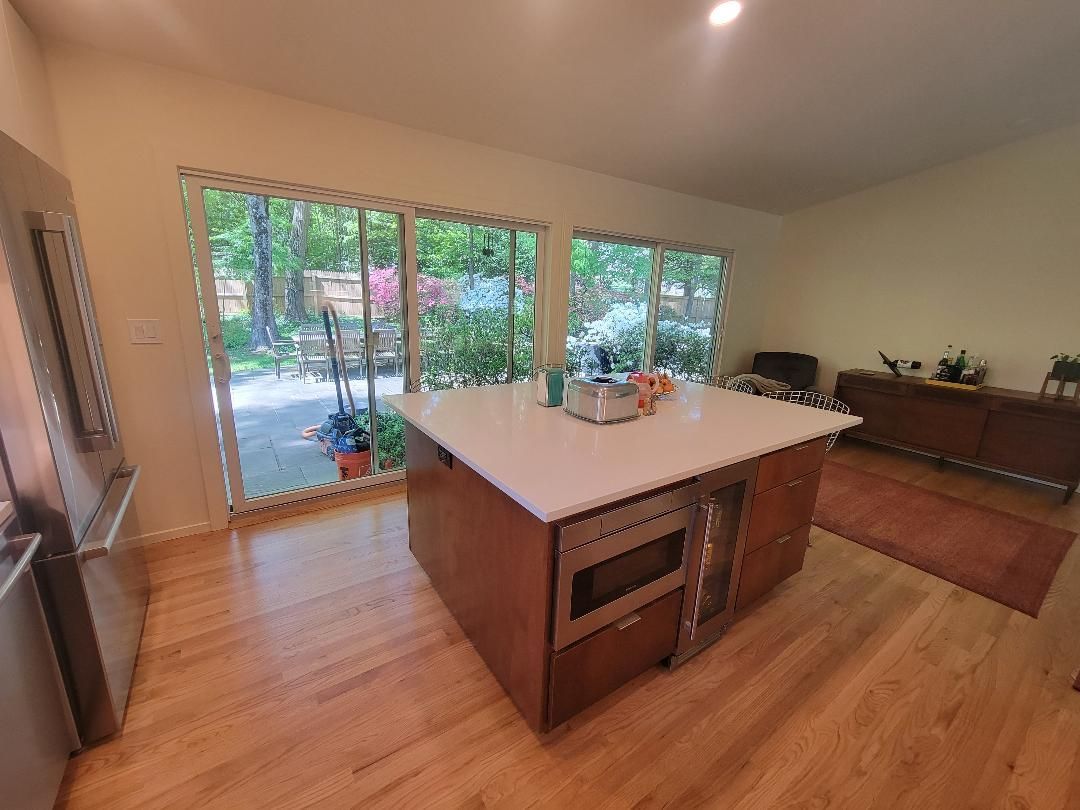 Wooden kitchen with island, stainless steel appliances, and large windows overlooking a garden.