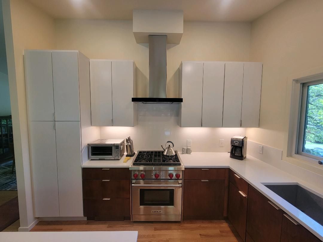 Modern kitchen with white upper cabinets, stainless steel appliances, and brown lower cabinets.