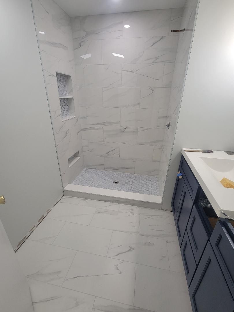 Bathroom with white marble tiled shower, blue vanity.