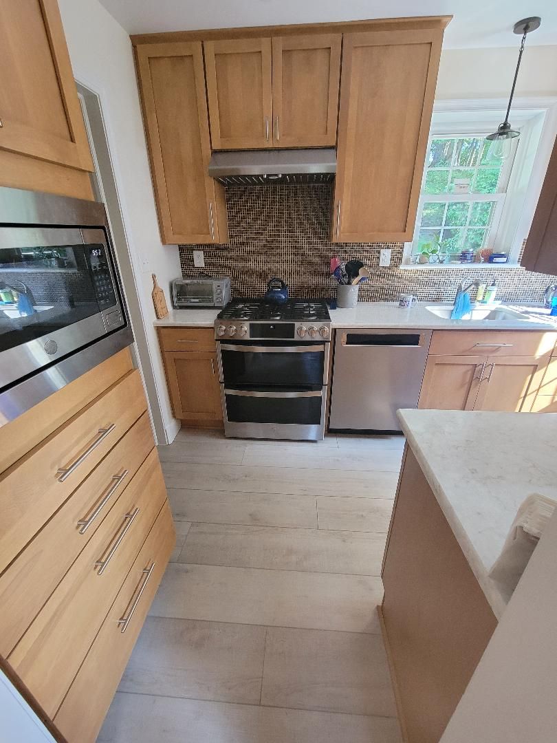 Kitchen with light wood cabinets, stainless steel appliances, and a patterned backsplash.