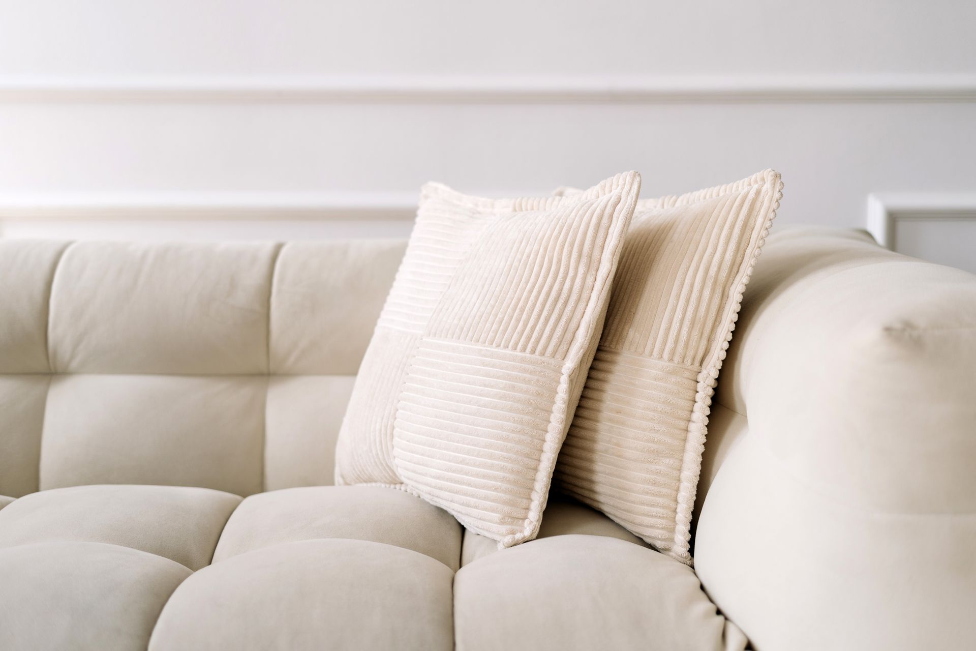 A white couch with three pillows on it in a living room.