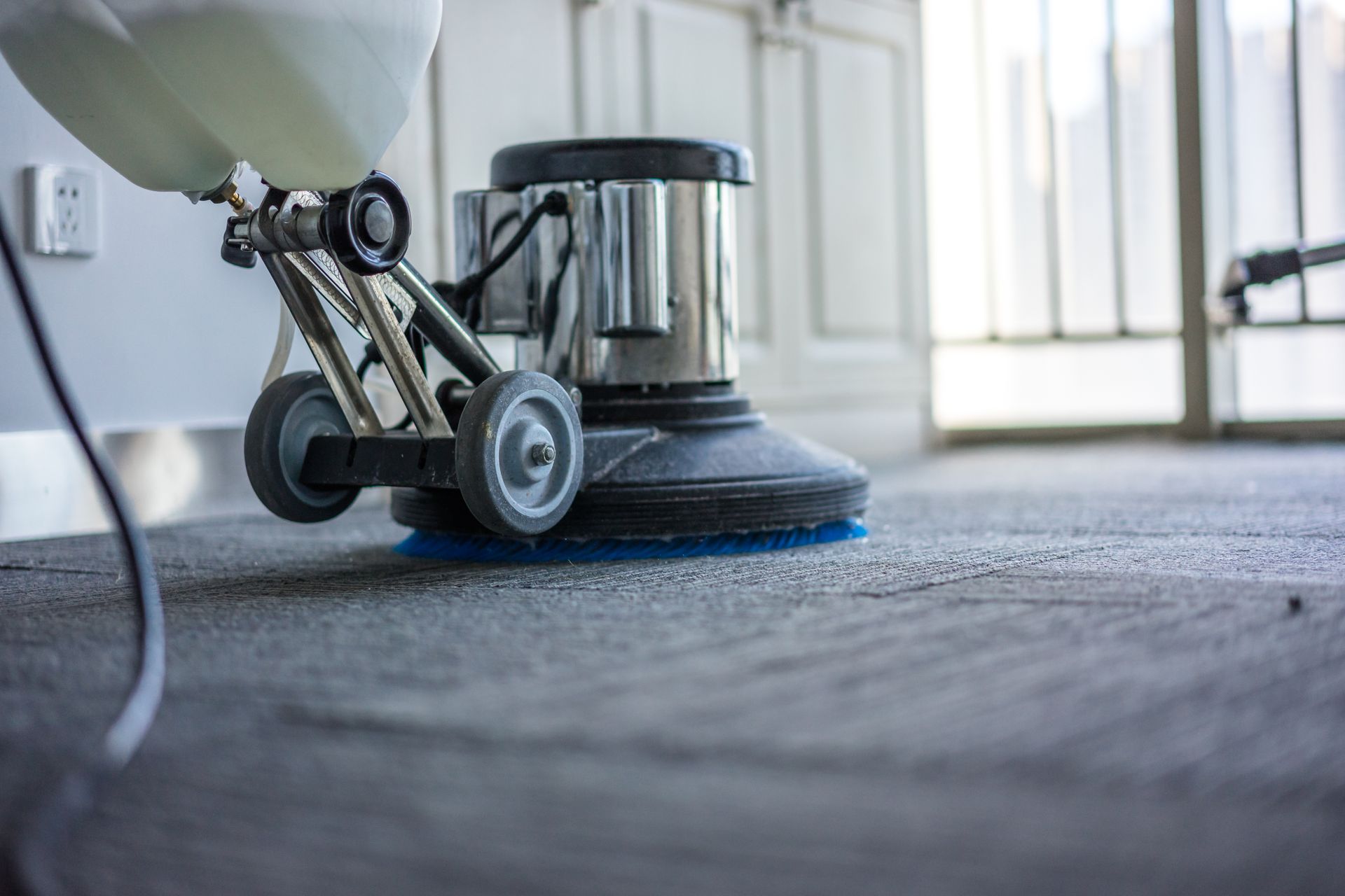 A vacuum cleaner is cleaning a carpet in a room.