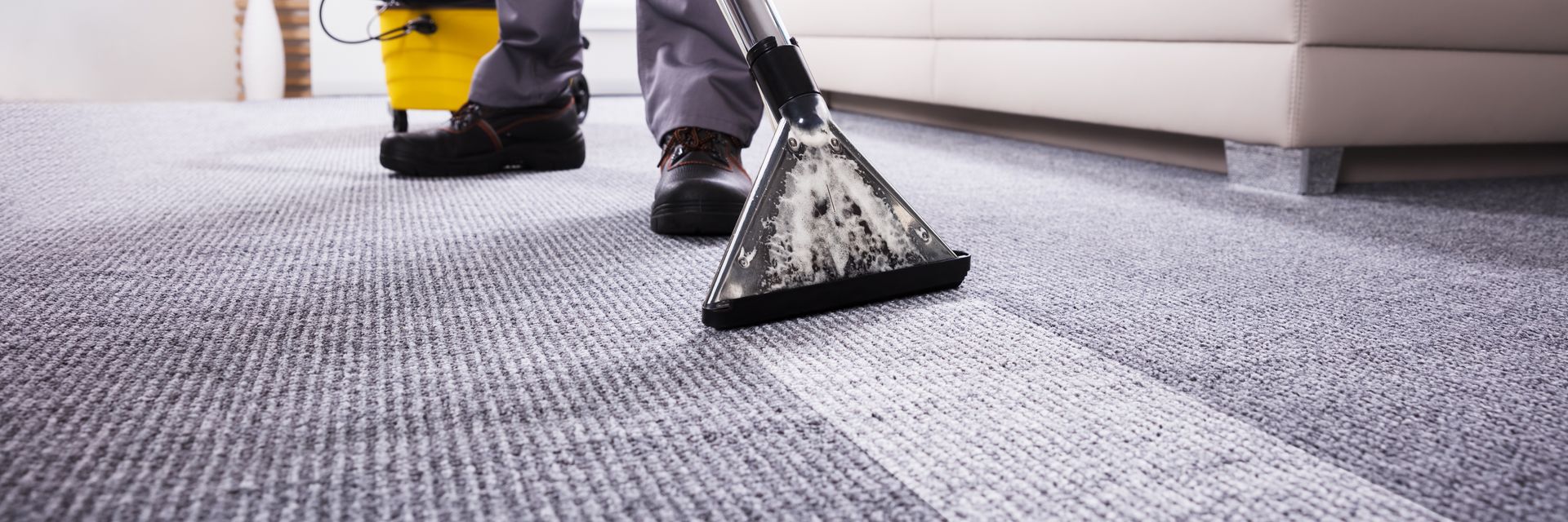 A person is cleaning a carpet with a vacuum cleaner.